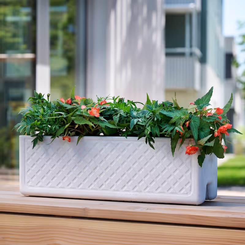 Weißes Swisspearl Balconia Reservoir Pflanzgefäß mit roten Blumen auf der Terrasse.