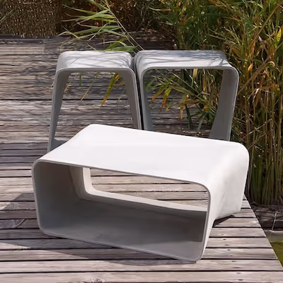 Swisspearl Ecal‑Stühle und Ecal‑Tisch auf Holzdeck mit Schilf im Hintergrund