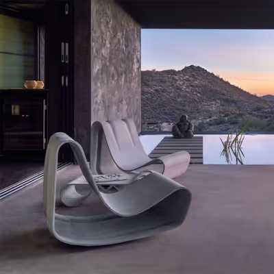 Geschwungener Swisspearl Guhl‑Stuhl auf einer überdachten Terrasse mit Blick auf Pool und Wüstenlandschaft im Sonnenuntergang.